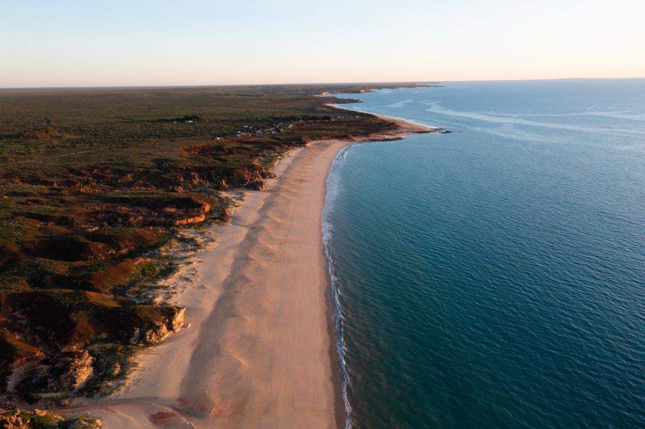 Glassy ocean meeting green shrub land in North-West Australia
