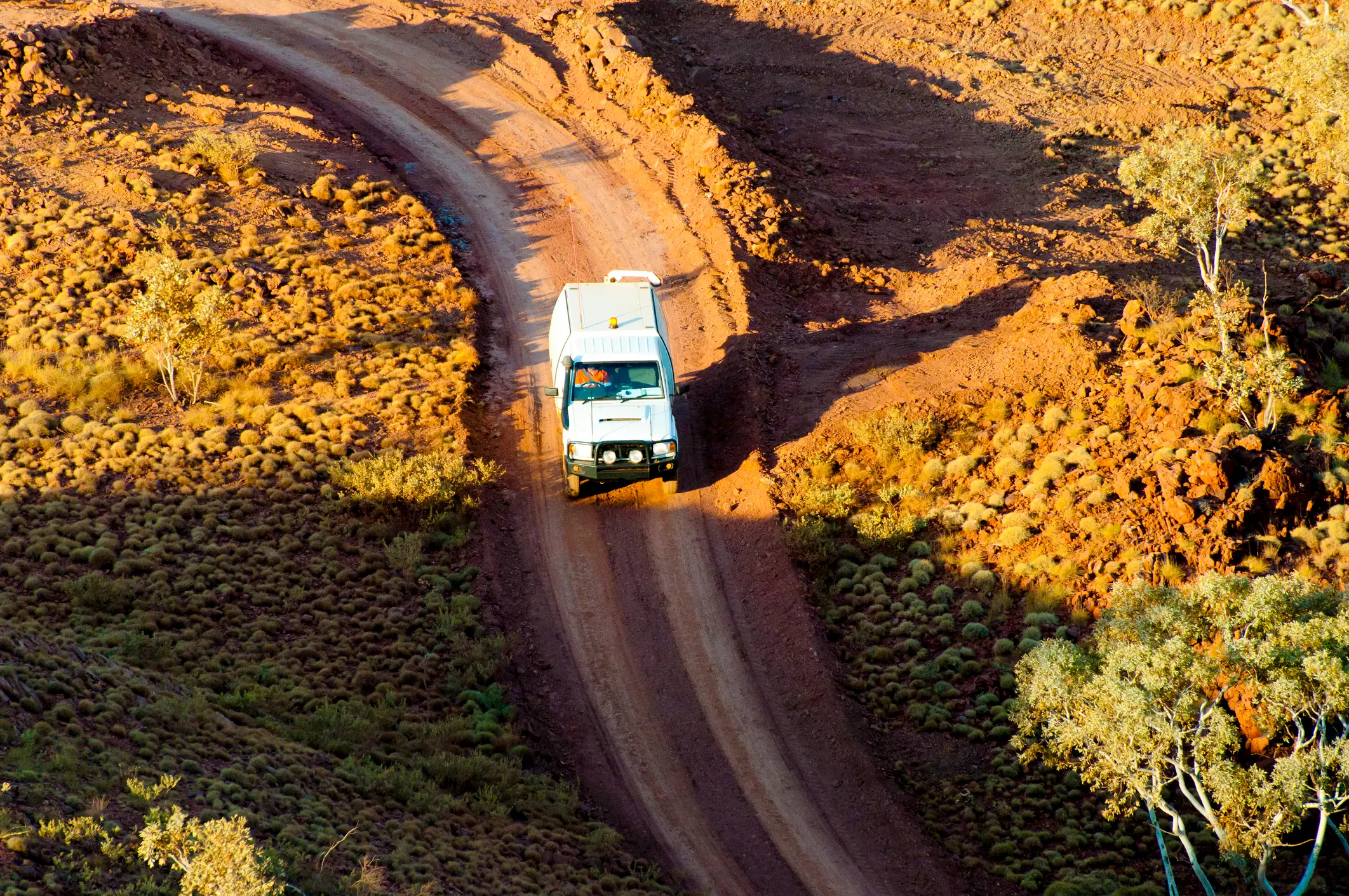Light vehicle travelling on a dirt road through remote North-West Australia