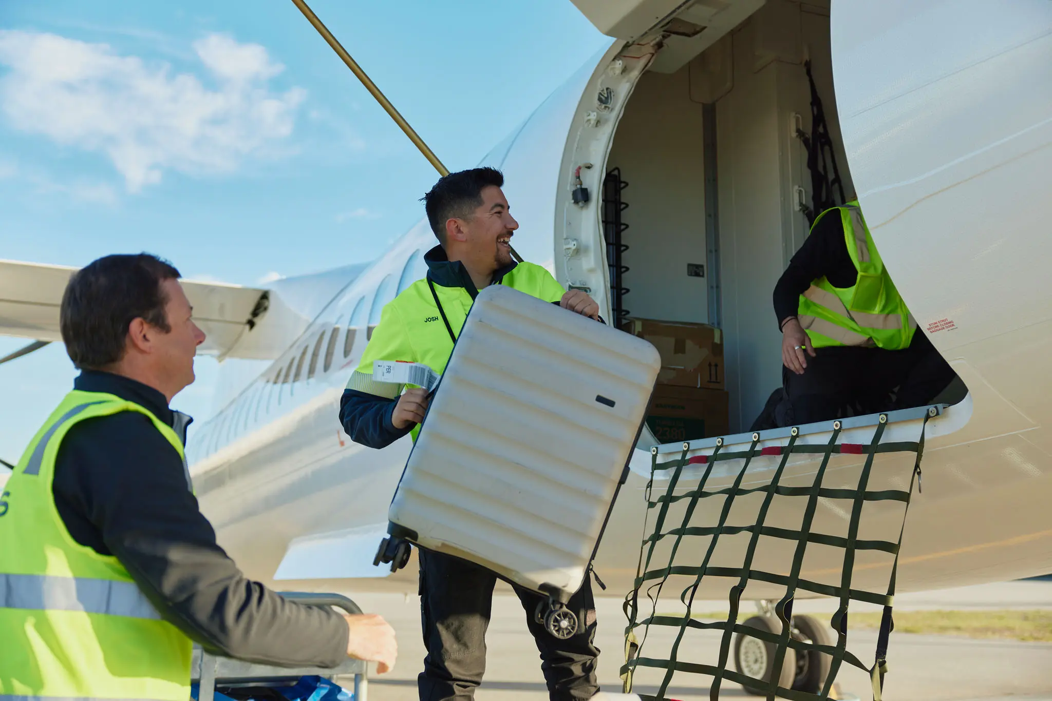 Three people loading luggage into a Nexus Airlines airplane