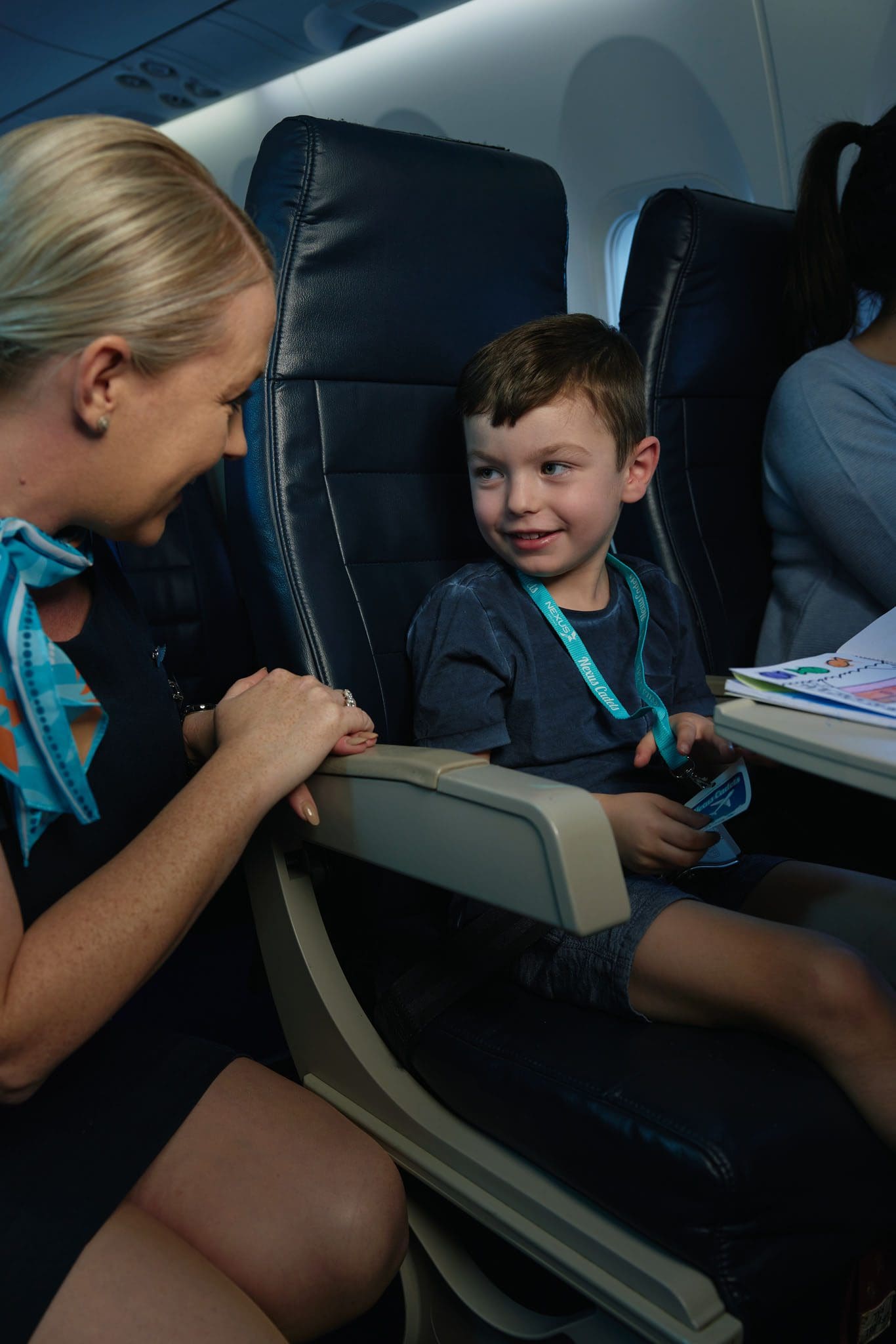 Flight attendant smiling at a young boy on a Nexus Airlines plane
