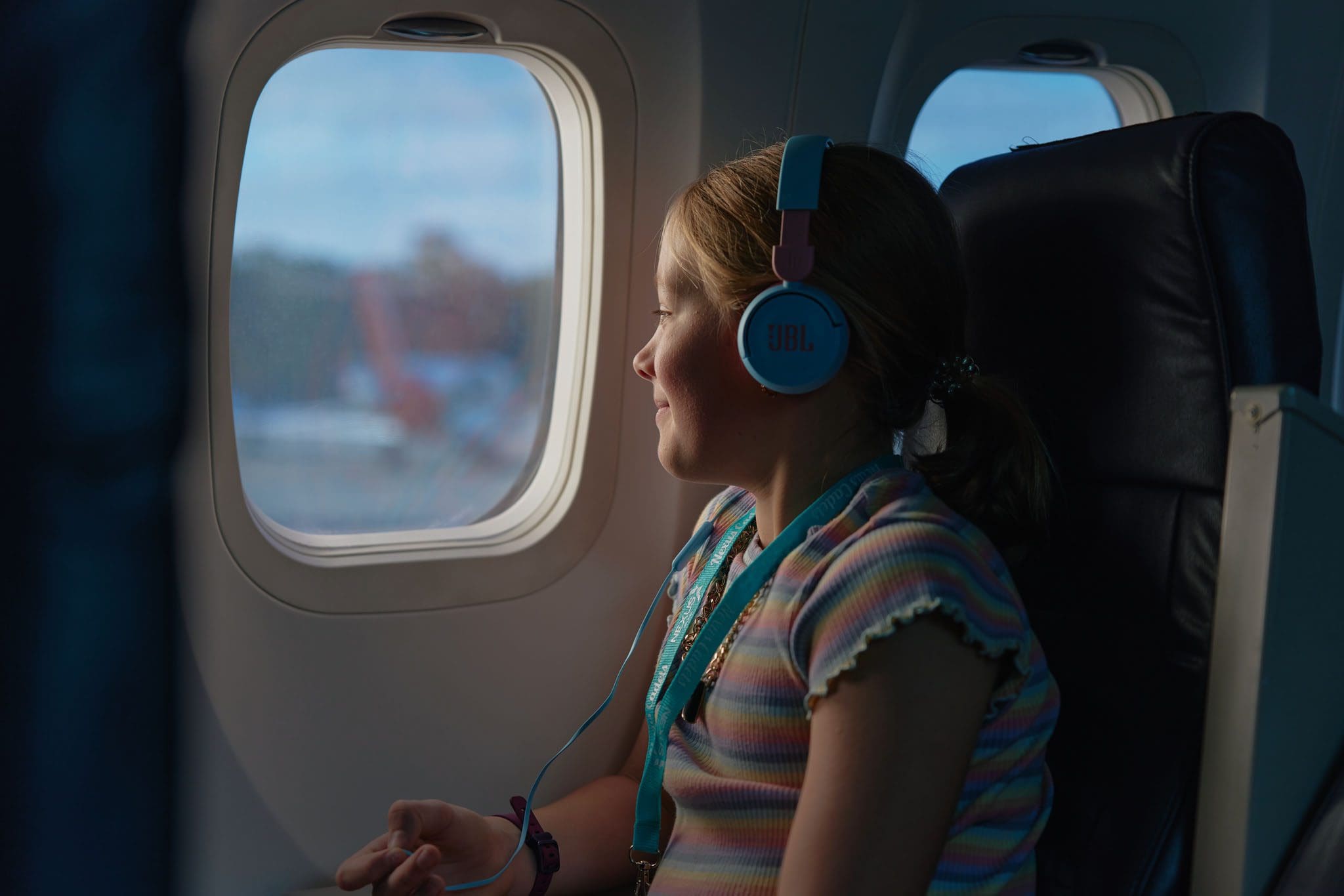 Young girl looking out the window of a Nexus Airlines plane prior to takeoff